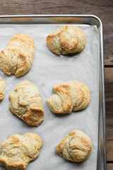 Flaky, golden biscuits on parchment paper on wooden table