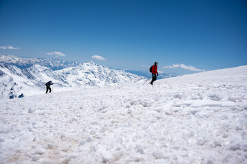 A group of people walking on the snowy mountains with their snowshoes on. Climbing the icy mountains