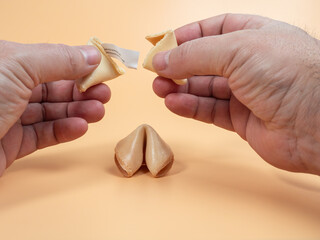 Male hands breaking fortune cookies on an orange background. Fortune cookies close up.