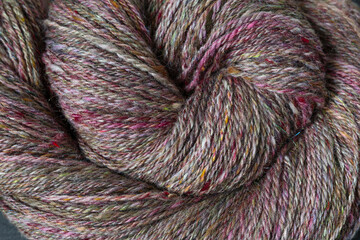Closeup detail of colourful hand spun sheep wool merino fibres, rolled up in a yarn ball skein,...