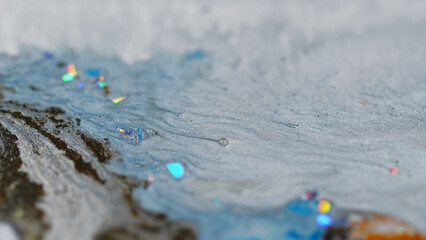 Glitter paint wave. Sparkling fluid flow. Defocused blue brown color glass particles emulsion ink...