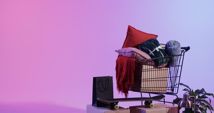 A shopping cart is filled with home decor items such as cushions and a throw blanket, with copy spac