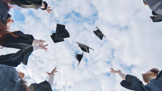 Happy college graduates tossing their caps up at sunset.