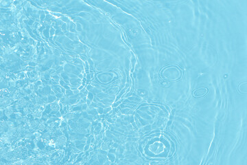 Bluewater waves on the surface ripples blurred. Defocus blurred transparent blue colored clear calm water surface texture with splash and bubbles. Water waves with shining pattern texture background.