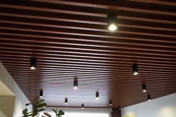 The ceiling is made of wooden slats with spotlights - obrazy, fototapety, plakaty