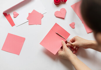 Woman is making pink origami paper heart for Valentine's day