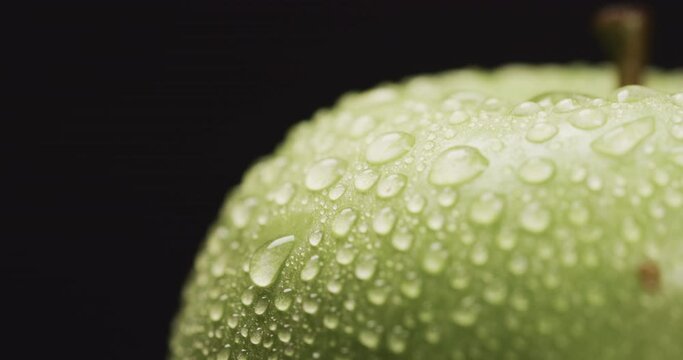 Close-up of water droplets on the surface of a green apple, with copy space
