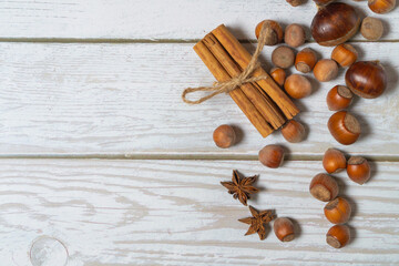 Hestnuts, star anise, cinnamon and cobnuts on a white wooden background with copyspace