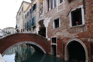 Fototapeta na wymiar Picturesque bridge stretches across a tranquil body of water in front of an old building in Venice