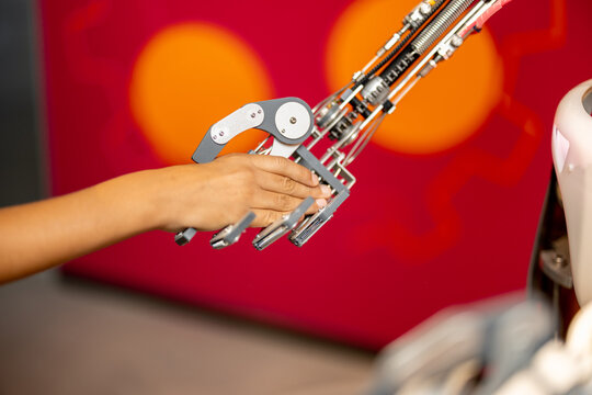 Kid shakes a hand with a robot, close-up. Concept of modern technologies and future with humanoid robots