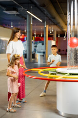 Mom with kids learn physics interactively on a model that shows physical phenomena while visiting a...