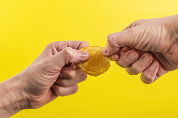 Potato chips in hand on yellow background