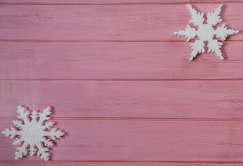 Two white snowflakes on a pink wooden background topview. New Years flatlay with copyspace