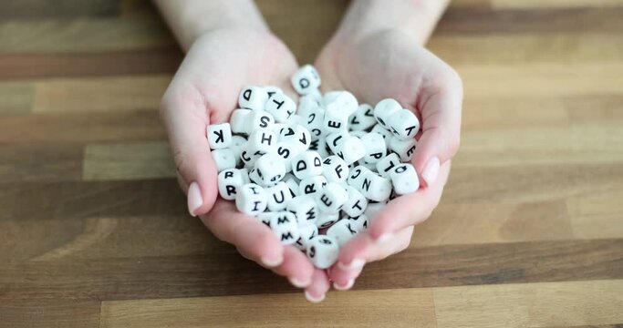 Hands hold and lot of white bones with English letters on table closeup. English language learning