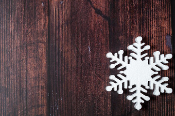 One snowflake on a brown wooden background. Christmas winter flatlay with copyspace	