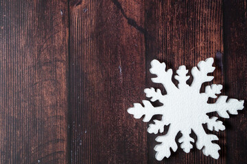 One snowflake on a brown wooden background. Christmas winter flatlay with copyspace	