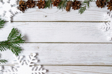 Topview of pine tree branches, pinecones, snowflakes  on wooden  white background. Christmas flatlay with copyspace