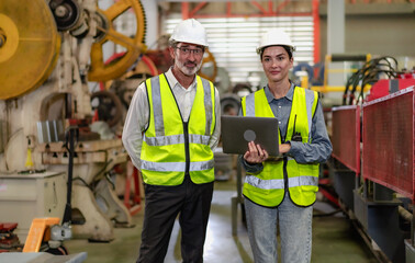 Senior manager train female technician working in metalwork production factory. Industrial engineer teamwork standing in manufacturing facility talking machinery maintenance in heavy steel industry.