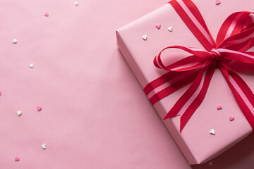 Valentine's day celebration gift box with red bow on the pink background. Close up