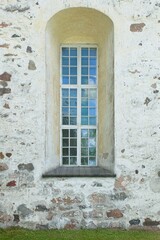 Wooden framed window with arch on a old stone building.
