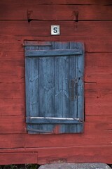 Weathered white framed black door on red building.