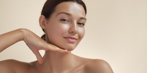 Happy beautiful young adult woman touching her perfect face with healthy shiny skin, hand on chin....