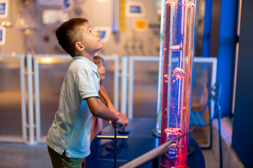 Little boy pump a bubbles into tubes studying physical phenomena in an interactive way, visiting...