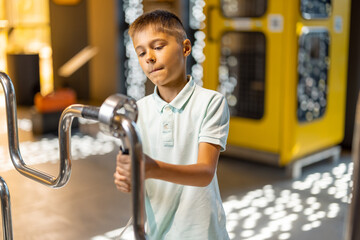 Little boy studying physics and electricity on an interactive model in the science museum. Concept...