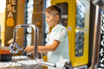 Little boy studying physics and electricity on an interactive model in the science museum. Concept of children's entertainment and learning