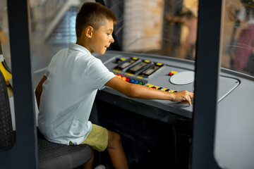 Little boy drives an old tram simulator in a science museum. Concept of children's entertainment...