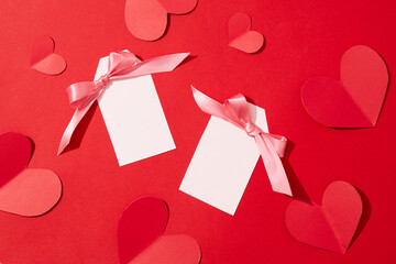 The two cards are decorated with pink ribbons, surrounded by paper hearts on a red background. Love...