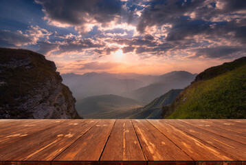 Summer beautiful background with sunrise over mountains and empty wooden table in nature outdoor....