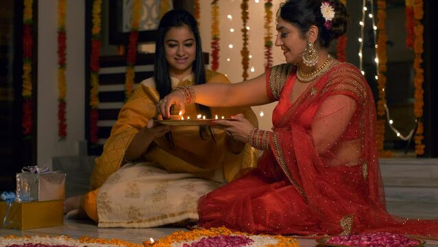 Diwali festival decoration - Happy mother and daughter decorating rangoli with diyas. 