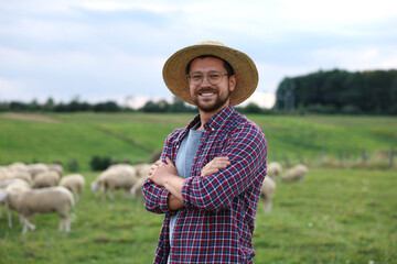 Portrait of smiling man with crossed arms on pasture at farm