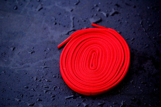 red shoe lace swirl design  on a wooden black ground background