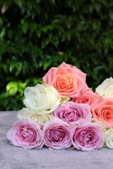 Beautiful bouquet of roses on light grey table outdoors, closeup