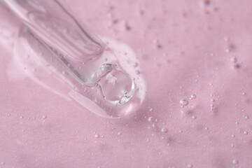 Pipette with cosmetic serum on pink background, closeup. Space for text