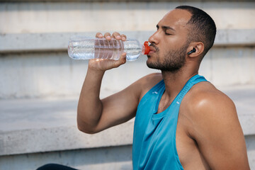 Man in sportswear having a break in workout and drinking water