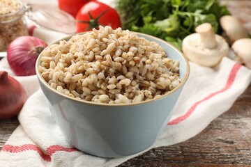 Delicious pearl barley in bowl served on wooden table, closeup