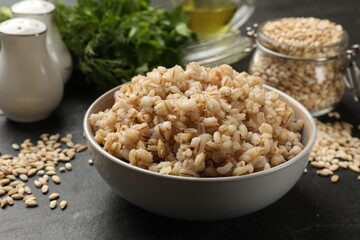 Tasty pearl barley porridge in bowl on dark table, closeup