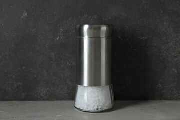 Salt shaker on light table against grey background, closeup