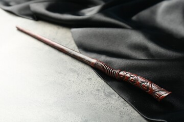Magic wand and dark cloth on light grey table, closeup