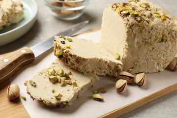 Tasty halva with pistachios and knife on grey table, closeup