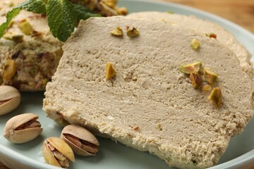 Tasty halva with pistachios and mint on table, closeup