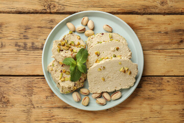 Tasty halva with pistachios and mint on wooden table, top view