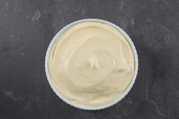 Fresh mayonnaise sauce in bowl on grey table, top view