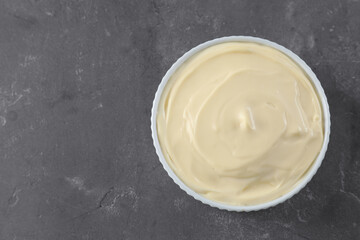 Fresh mayonnaise sauce in bowl on grey table, top view. Space for text