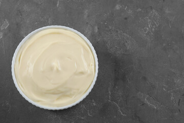 Fresh mayonnaise sauce in bowl on grey table, top view. Space for text