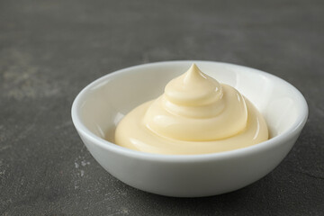 Fresh mayonnaise sauce in bowl on grey table, closeup