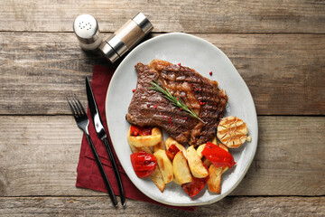 Delicious grilled beef steak and vegetables served on wooden table, top view